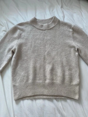 Beige stickad tröja från H&M XS - Mysig beige stickad tröja från H&M i storlek XS. Tröjan har en ribbad halsringning och ribbade muddar vid ärmslut och nederkant. Perfekt inför våren när det fortfarande är lite kallt. Använd men inte sönder eller liknande. 