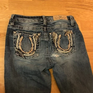 Miss Me jeans med broderade fickor - Säljer ett par ljusblå miss me jeans då de inte kommer till användning längre. Har liten slitning vid slutet av benet och i rumpan men skulle inte säga att det är så synligt. Jeansen är stretchiga. 
