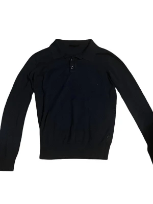 Svart långärmad pikétröja - Klassisk svart pikétröja med lång ärm och krage. Tröjan har två knappar vid halsen och är tillverkad i ett mjukt material som känns skönt mot huden. Perfekt för dig som gillar en stilren och enkel look. Storleken är M men skulle säga att det känns som S-XS. Färgen är mörkblå.