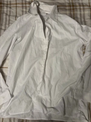 Vit skjorta från Selje, storlek 38 - Klassisk vit skjorta från Selje i storlek 38. Skjortan har lång ärm, knappar framtill och en snygg krage. Perfekt till jeans eller kostymbyxor för en clean look. Tillverkad i mjukt bomullstyg som känns skönt mot huden.