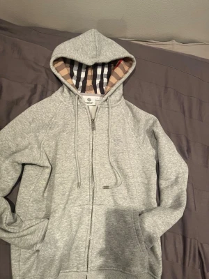 Burberry zip-up grå - Burberry grå zip-up hoodie – helt ny Helt ny och oanvänd Burberry zip-up hoodie i grå färg. Stilren och tidlös design med hög kvalitet och skön passform. Aldrig använd, i perfekt skick. Perfekt både till vardags och finare outfits.