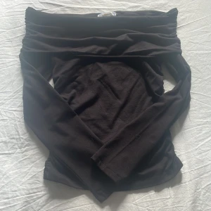 Svart offshoulder långärmad topp Gina Tricot - Svart långärmad topp från Gina Tricot med snygg offshoulder-design. Mjuk och stretchig bomullskvalitet som sitter skönt mot kroppen. Perfekt för dig som gillar stilrena och enkla plagg med en twist. Passar dig som vill ha en cool och trendig look.