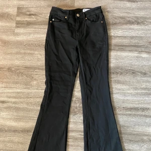 Svarta bootcut jeans från Vero Moda - Svarta jeans från Vero Moda med klassisk femficksdesign och bootcut-ben. Snygg passform med normal midja och diskreta detaljer. Perfekta för dig som gillar en stilren look med lite utsvängda ben. Materialet är mjukt och stretchigt för extra komfort. Storlek xs