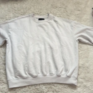 Vit sweatshirt från 157, storlek M - En basic vit sweatshirt från 157 i storlek M. Tröjan har rund halsringning, ribbade muddar vid ärmslut och nederkant samt lång ärm. Perfekt för en chill och avslappnad stil. Materialet känns mjukt och skönt mot huden. 