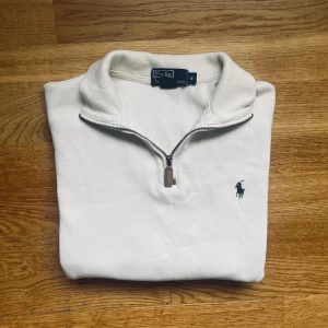 Vit half zip tröja från Polo Ralph Lauren - Vit half zip från Ralph lauren, passar perfekt nu till hösten.   Storlek S i väldigt bra skick, endast en väldigt liten fläck vi ser på bild 4. Inget märkvärdigt. Tröjan är äkta. Hör av dig vid fler frågor 