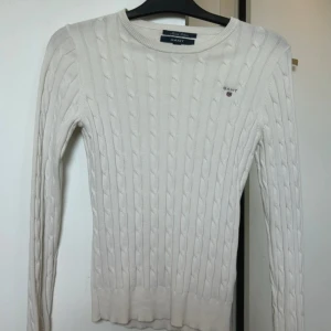 Vit kabelstickad tröja från GANT XS - Vit kabelstickad tröja från GANT i stretchig bomull. Klassisk rund halsringning, diskret GANT-logga broderad på bröstet och ribbade muddar. Snygg och tidlös modell som passar perfekt till jeans eller kjol. Skriv gärna om ni är intresserade! Går nog med på de flesta prisförslag😊kom privat så diskuteras pris! 