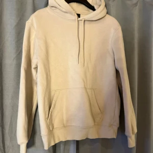 Beige hoodie från H&M, relaxed fit - En stilren beige hoodie från H&M i relaxed fit. Tröjan har huva med snörning, magficka och långa ärmar. Perfekt för en chill look och enkel att matcha med jeans eller mjukisbyxor.