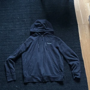 Mörkblå zip up hoodie från Armani Exchange - Mörkblå hoodie från Armani Exchange med dragkedja framtill och snörning i huvan. Klassisk passform med långa ärmar och diskret logga på bröstet. Perfekt för en chill och stilren look. Storlek M men passar även S. Nypris 1800 kr.   Pris kan diskuteras