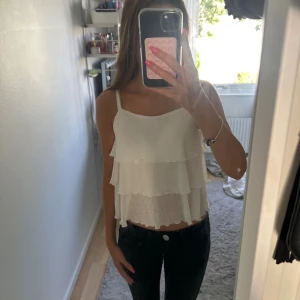 Vit volang-linnetopp från Kappahl - Säljer en söt vit linnetopp från Kappahl med tunna axelband och dubbla volanger. Toppen är luftig och perfekt för varma dagar, med en lätt och flowy känsla. Enkel att matcha med både jeans och kjol 💗💗