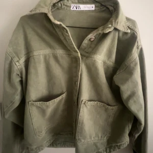 Grön jeansjacka från Zara - Snygg ljusgrön jeansjacka från Zara med klassisk krage, stora fickor framtill och knäppning med metallknappar. Jackan har en rak passform och är tillverkad i bomull, perfekt för lager-på-lager-stil. Enkel att matcha till olika outfits.