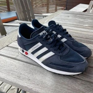 Adidas LA Trainer sneakers marinblå - Säljer ett par Adidas LA Trainer skor i marinblå färg, storlek 44&2/3. Snygga och stilrena skor som passar perfekt till sommaren men även nu till vintern. Skorna är inte använda mycket. Skorna är i jätte bra skick och sulan är som ny. Skick 9/10. Kan gå ner i pris vid snabb affär. Hör av er vid frågor! /Oskar