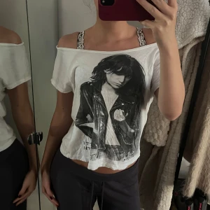 Vit offshoulder t-shirt med tryck - Säljer en vit t-shirt i bomull med offshoulder-modell och korta ärmar. Framsidan har ett stort svartvitt tryck av en person i skinnjacka. 