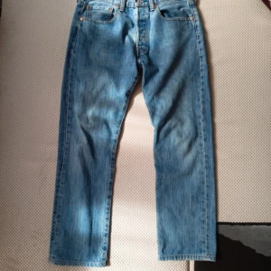 VINTAGE Levi's 501 ljusblå jeans straight fit  - Klassiska Levi's 501 jeans i ljusblå denim med raka ben och normal passform. Byxorna har fem fickor, knappgylf och ikonisk läderpatch bak i midjan. Perfekta för dig som gillar en tidlös och avslappnad look.