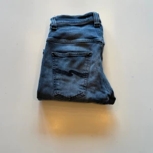 Nudie Jeans blåa - Snygga blå jeans från Nudie Jeans med klassisk femficksdesign. Jeansen är tillverkade i mjukt denimtyg och har subtila slitningar för en cool look.