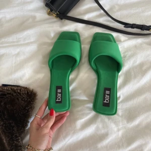 Gröna sandaler med klack från Bar III - Snygga gröna sandaler från Bar III med fyrkantig tå och låg klack i rund form. Skorna har bred rem över foten och är tillverkade i syntetmaterial. Perfekta för att ge en pop av färg till din outfit.