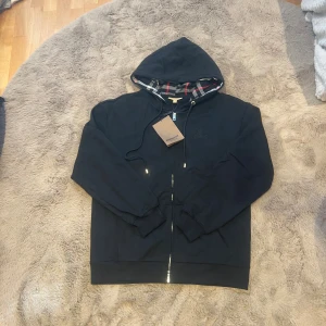 Burberry zip up svart - Burberry Zip-Up Hoodie black – Storlek M  ✅ – tag kvar, men kvitto saknas 🧼 Helt oanvänd – inga märken, fläckar eller skador 📦 Originalpåse skickas väl emballerad  ⚠️ Säljes p.g.a. fel storlek 📍 Möts upp i Göteborg eller skickas spårbart  Skicka ett meddelande om du är intresserad eller har frågor!