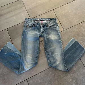 Snygga lågmidjade jeans - Snygga ljusblå jeans med bootcut passform och slitna detaljer. Jeansen har klassisk femficksdesign, låg midja och coola broderade bakfickor. Säljer pga dom inte passar mig, förra ägaren sydde ner dom så dom är extra lågmidjade. Inrebenmått ca 75 midjemått ca 40.  Skriv vid frågor eller intresse🥰🥰