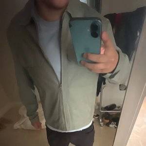 Overshirt jacka  - Snygg ljusgrön overshirt med dragkedja framtill och två bröstfickor. Jackan har en clean look och är perfekt för lager-på-lager. Passformen är normal och materialet känns mjukt och lätt. Perfekt för dig som gillar stilrena plagg. 