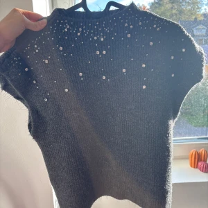 Mörkgrå stickad tröja med paljetter - Mysig mörkgrå stickad tröja med korta ärmar och glittrande paljettdetaljer upptill. Tröjan har en ribbad struktur och är perfekt för dig som vill ha något extra snyggt och unikt i garderoben.Stockholm stil💕