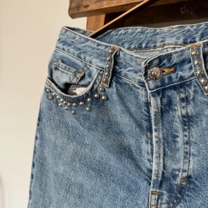 Blå jeans med nitar och raka ben - Snygga ljusblå jeans med raka ben och  silverfärgade nitar längs fickorna och hällorna. Jeansen har klassisk femficksdesign. 