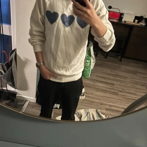Snygg vit sweatshirt - Vit sweatshirt från Jerzees i storlek M med tre stora blå hjärtan på bröstet. Tröjan har rund hals, långa ärmar och ribbade muddar. Perfekt för dig som gillar en stilren klädstil. ⭐️Aldrig använd, ⭐️Storlek M, ⭐️Pris 200kr(går att förhandla) skriv till mig om ni har några frågor. Förlåt för skrynklig tröja…
