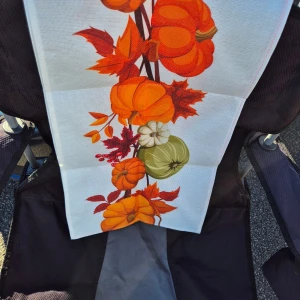 Bordsduk höstlov. - Bilderna visar en textil med färgglada pumpor och höstlöv. Produkten verkar vara en dekorativ duk eller tygstycke med hösttema.