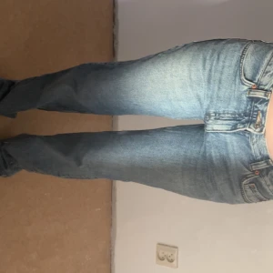 Lågmidjade straight leg jeans - Säljer ett par klassiska jeans i ljusblå tvätt med raka ben och hög midja. Jeansen har fem fickor, knappgylf .Perfekt vintage vibe och snygg passform som sitter skönt över höften.