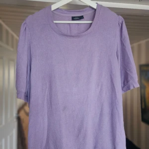 Ljuslila stickad tröja KappAhl - Superfin ljuslila tröja från KappAhl med rund halsringning och korta ärmar. Perfekt för dig som vill ha en enkel men ändå söt look. Mjuk och skön, passar till både jeans och kjol.