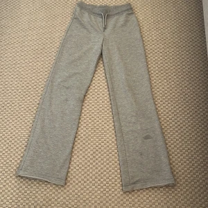 Grå mjukisbyxor med snörning - Grå mjukisbyxor i bomullsmix med raka ben och bred resår i midjan. Byxorna har snörning framtill för justerbar passform och en enkel, stilren look. Perfekta för chill dagar eller när du vill vara extra bekväm. Har en fläck men syns inte.🩷