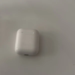 Apple AirPods (2nd generation) - Apple AirPods 2nd gen med laddningsetui. Trådlösa hörlurar med bra batteritid och snabb anslutning till Apple-enheter. Viss smuts och tecken på användning syns på etuiets insida och hörlurarna, men fungerar som de ska.