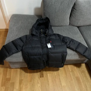 Svart Polo Ralph lauren (Down jacket) - Snygg svart Polo Ralph Lauren i storlek L till salu! ( Passar även M )Klassisk design med den ikoniska loggan på bröstet. Tröjan är i mycket gott skick och perfekt för både vardag och lite mer uppklädda tillfällen. Passar dig som vill ha en tidlös och stilren look. Hör av dig vid intresse! Priset kan diskuteras 😁