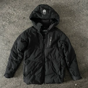 Sail racing jacka - Svart sail racing jacka. Jackan har dragkedja framtill, två sidofickor och en bröstficka med logga. Fodrad insida och quiltad design som håller värmen. Perfekt för kalla dagar och snygg. Passar storlek S och M 170cm till 180. Pris kan diskuteras vid snabb affär.