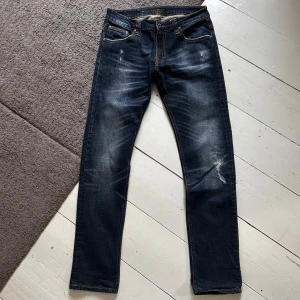 Mörkblåa Nudie Thin Finn Jeans - Galet snygga Nudie jeans med en galant wash & stilrena slitningar i Thin Finn modell. | W32 L32 | Nypris 1699kr | Som nya, riktigt bra skick. | Längd ca 107cm, midja ca 41cm. | Skriv vid minsta fundering, priset är ej hugget i sten!