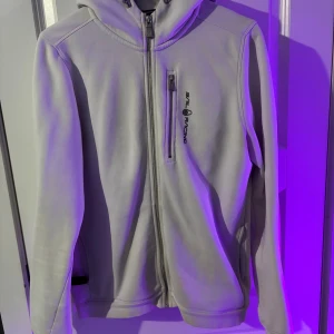 Sail Racing hoodie - Säljer en stilren vit hoodie från Sail Racing med hel dragkedja framtill och en extra ficka med dragkedja på bröstet. Passar S och small M