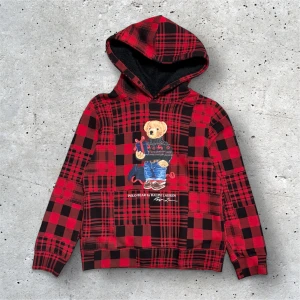 Polo Ralph Lauren Bear i nyskick - Ikoniska Polo Bear hoodie från Polo Ralph Lauren. Tröjan har huva med mjukt foder, långa ärmar och är tillverkad i bomull och polyester. Perfekt statement-plagg med snygg julkänsla och coolt tryck framtill. Nypris 1995kr från Kidsbrandstore. 