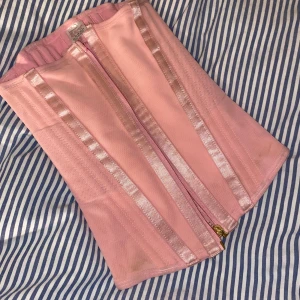 Rosa korsett med dragkedja XXS - Säljer en ljusrosa korsett med dragkedja framtill och hakar på insidan. Den sitter jätte bra på på kroppen!!                                                                                                   Passar xs också 