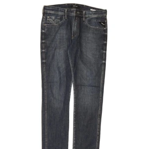 Replay Anbass jeans mörkblå herr - Snygga Replay Anbass jeans i mörkblå tvätt med klassiska fem fickor och coola kontrastsömmar på bakfickorna. Jeansen har rak passform och är tillverkade i en stretchig bomullsblandning för extra komfort. Perfekta för en avslappnad och stilren look.