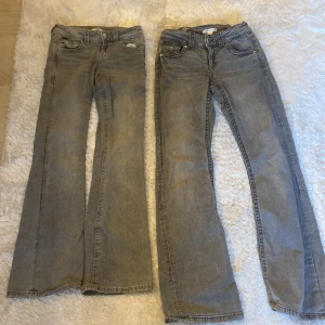 Grå bootcut jeans med detaljer. Båda jeansen för 500kr. - Två par grå bootcut jeans med klassisk femficksdesign. Ena paret har snygga broderade detaljer och silvriga knappar på bakfickorna. Båda har låg midja och är tillverkade i mjukt jeanstyg. Perfekta för dig som gillar en avslappnad och trendig look. Den med broderier är storlek 152 och den utan är i storlek 158. Bra skick .