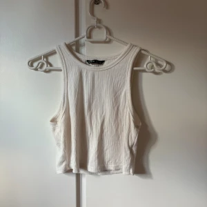 Vit ribbad linnetopp från SHEIN - Säljer en vit ribbad linnetopp från SHEIN i storlek XS. Toppen är ärmlös med rund halsringning och croppad passform. Perfekt för varma dagar och enkel att matcha med jeans eller kjol. Materialet är mjukt och stretchigt för en bekväm känsla.