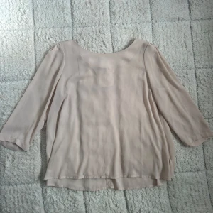 Beige blus från Monki - Säljer en flowy beige blus från Monki i storlek Large. Blusen har trekvartsärmar, rundad hals och snygga tygklädda knappar i ryggen. Tillverkad i ett tunt och lätt polyestertyg som ger en chill och luftig vibe.