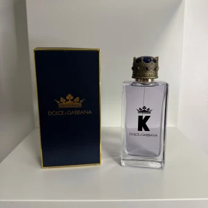 Dolce & Gabbana K Eau de Toilette 100ml - Säljer en Dolce & Gabbana K Eau de Toilette, 100 ml. Flaskan är transparent med lila doftvätska och har en snygg kronformad kork i guld och blått. Kommer med originalförpackning i mörkblått med gulddetaljer. Perfekt för dig som gillar lyxiga och stilrena parfymer.
