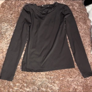 Svart långärmad topp Design by Si - En stilren svart långärmad topp från Design by Si. Toppen har en enkel och clean design med rund halsringning och är tillverkad i ett mjukt, stretchigt material som sitter snyggt på kroppen. Perfekt att styla med jeans eller kjol.