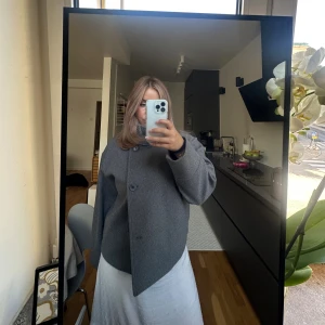 Grå kappa med stor krage - Säljer en grå kappa med stor krage. Stängs med stora knappar framtill. Aldrig använd från Gina så i nyskick däremot inga prislappar kvar