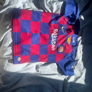 FC Barcelona Messi 10 matchtröja Nike - Säljer en officiell FC Barcelona matchtröja från Nike med Messi 10-tryck på ryggen. Tröjan har klassiskt rödblått rutmönster, korta ärmar och är tillverkad i Dri-FIT material som andas. Perfekt för dig som älskar Barca och Messi! Storlek 147-158 cm och är ifrån säsongen 19-20