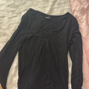 Svart långärmad topp Gina Tricot - En svart långärmad topp från Gina Tricot i mjuk bomull. Modellen har en djup rundad halsringning och sitter snyggt med normal passform. Perfekt att styla med jeans eller kjol för en enkel och clean look.