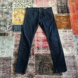 Mörkblå jeans från BOSS - Snygga mörkblå jeans från BOSS, modell 020 Delaware Slim Fit. Klassisk femficksdesign och diskret BOSS-läderpatch bak i midjan. Jeansen är tillverkade i ett stretchigt denimtyg som är väldigt snyggt med en cool tvätt. Str 34 sitter som 32. Skick 9/10. Pris 299. Skriv vid frågor!