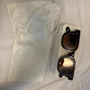 Svarta solglasögon CHIMI - Snygga svarta solglasögon från CHIMI med fyrkantig form och bruna tonade glas. Kommer med vit hård förvaringsbox och vit tygpåse med logga. Designade i Stockholm, perfekt för dig som gillar stilrena accessoarer.