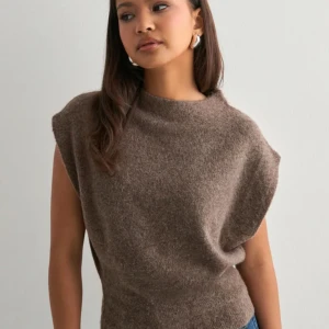 Brun ärmlös stickad topp - Säljer en brun stickad topp med ärmlös design och rund hals. Toppen har en loose passform och är gjord i mjukt stickat material som känns skönt mot huden. Perfekt att styla med jeans eller kjol. Ny med prislapp, skickar tillbaka den ifall ingen vill ha den🥰
