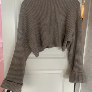 Beige ribbad croppad tröja Zara - Supermjuk och ribbad croppad tröja från Zara i beige. Tröjan har långa ärmar med breda muddar och en loose passform. Perfekt för lager-på-lager och chill dagar. Materialet är stickat och känns riktigt cozy.