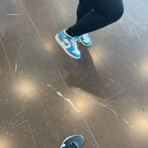 Nike Jordan 1 blå och vita sneakers - Snygga Nike Jordan 1 sneakers i blått och vitt med klassisk hög siluett och vit sula. Skorna har snörning och den ikoniska swoosh-loggan på sidan. Köpt i Täby 